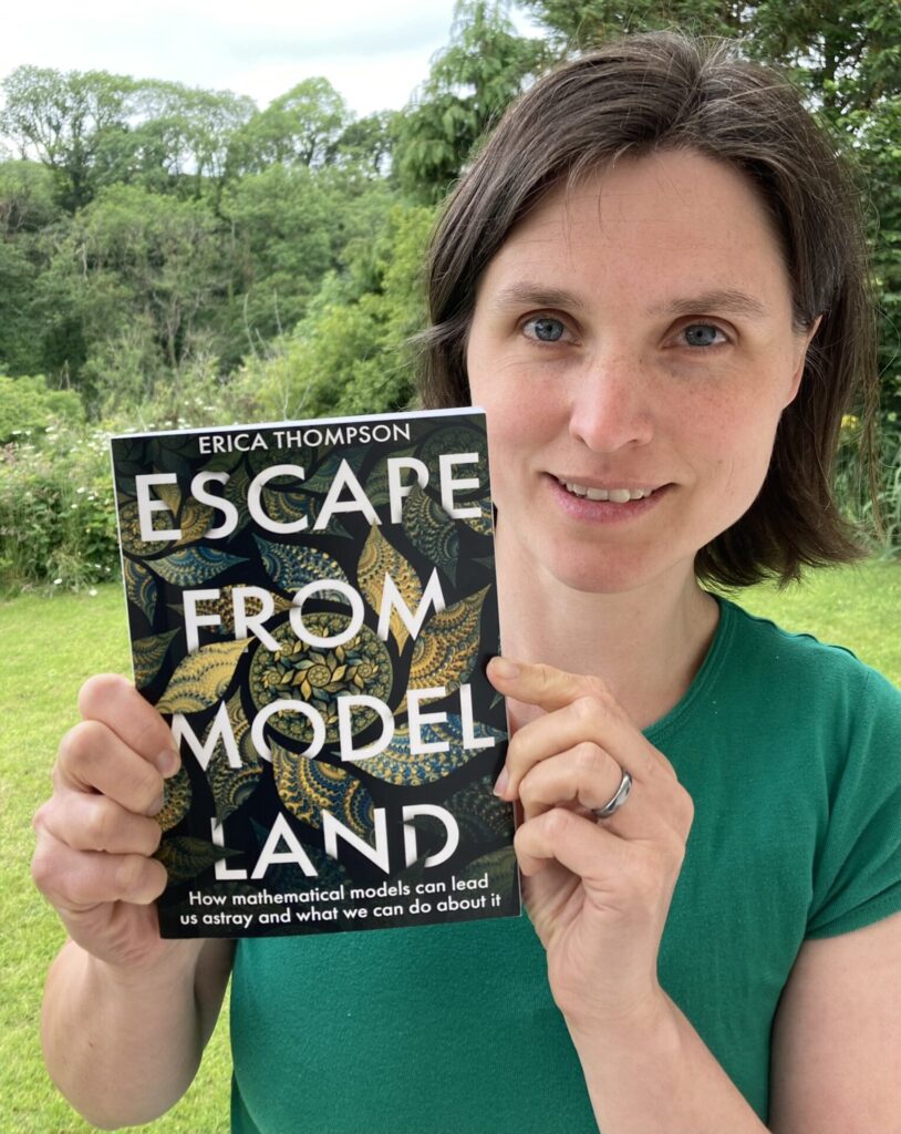 Headshot of Erica Thompson, holding her book titled 'Escape from Model Land'. 